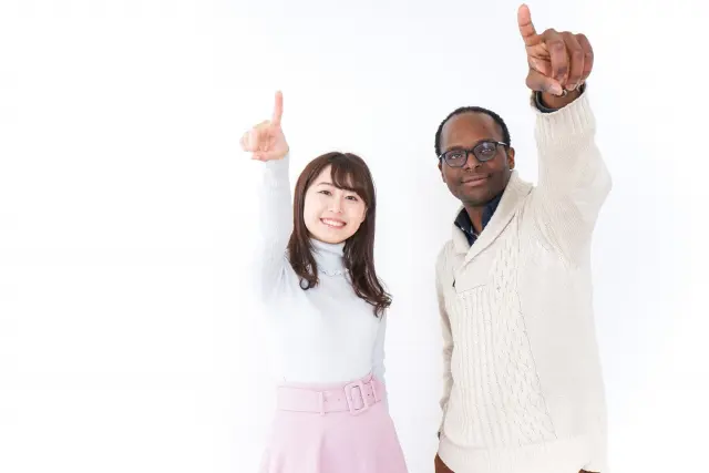 
アフリカ系男性と日本人女性が未来を見据えるように一緒に上を指さしているシーン。自毛植毛の治療方針や仕上がりイメージを共有するポジティブなカウンセリング風景を表現したストック画像。