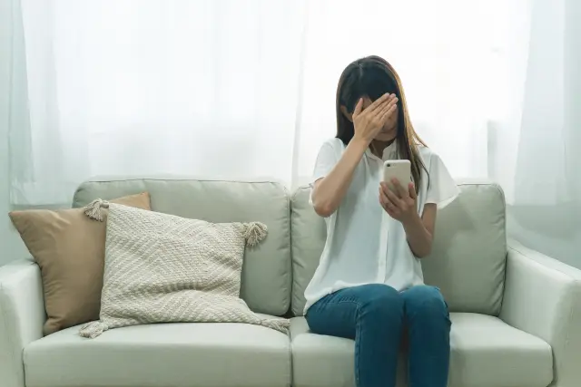 顔を手で覆い、落胆した表情を浮かべる女性。植毛手術で想定外のトラブルに直面した患者の不安や後悔を象徴するイメージ写真