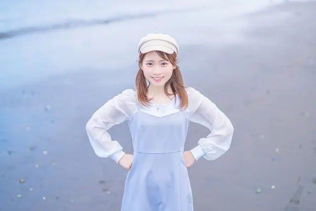 がん治療中の外見ケアに前向きな気持ちで取り組む若い女性が、白いキャップをかぶって海辺で笑顔を見せている様子。頭皮冷却キャップを連想させる装いで、心の回復と自分らしさの大切さを象徴するイメージ。