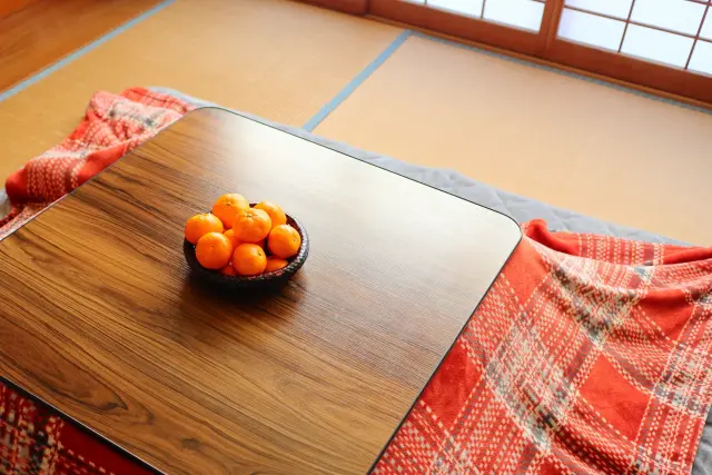 冬のこたつの上に置かれた籠のみかん。くつろぎの象徴であると同時に、ビタミンCを豊富に含み、髪の健康維持や毛包の酸化ストレス軽減に役立つ栄養源として、毛髪再生の文脈にもつながる季節の果物。