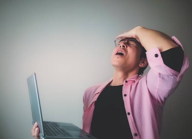 衝撃を受けて後ろにのけぞり、額に手を当てる男性。無資格者による植毛手術の実態を知り驚く患者のリアクションを表現したイメージ写真