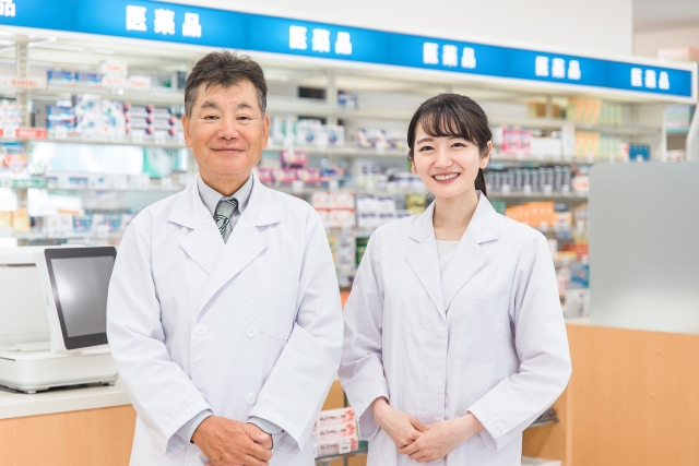 白衣を着た男女の薬剤師が薬局内に立つ様子｜市販の薄毛治療薬を販売する薬局と専門医による診断の違いを象徴するイメージ