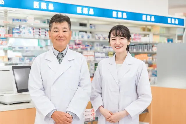 白衣を着た男女の薬剤師が薬局内に立つ様子|市販の薄毛治療薬を販売する薬局と専門医による診断の違いを象徴するイメージ