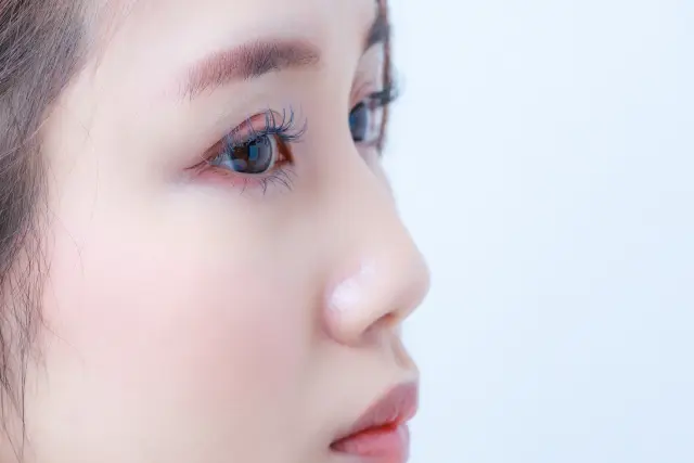 感情を読み取りにくい無表情の女性の顔のクローズアップ写真｜脱毛に悩む女性が自覚症状に戸惑いながらも気づきを得る瞬間を象徴するイメージ｜女性の脱毛症に関する啓発コラム用画像