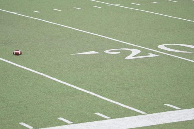 NFLフィールドの20ヤードライン付近に置かれたアメリカンフットボール。ウェス・ウェルカーが活躍したフットボールの舞台と、薄毛の悩みを乗り越えた植毛体験を象徴するイメージ。