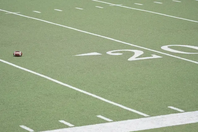 NFLフィールドの20ヤードライン付近に置かれたアメリカンフットボール。ウェス・ウェルカーが活躍したフットボールの舞台と、薄毛の悩みを乗り越えた植毛体験を象徴するイメージ。
