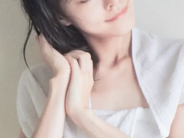 お風呂上がりの女性がウールタオルで黒髪を乾かしているシーン。微笑みを浮かべた口元が印象的。健康な髪は多くの人が当たり前に思っているが、失って初めてその大切さを実感することが多い。