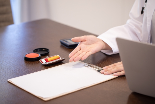 書類と印鑑が整い、正式な同意や契約直前に手で確認を示す様子｜自毛植毛の施術契約前に医師の資格・責任体制を確認する重要性を示すイメージ