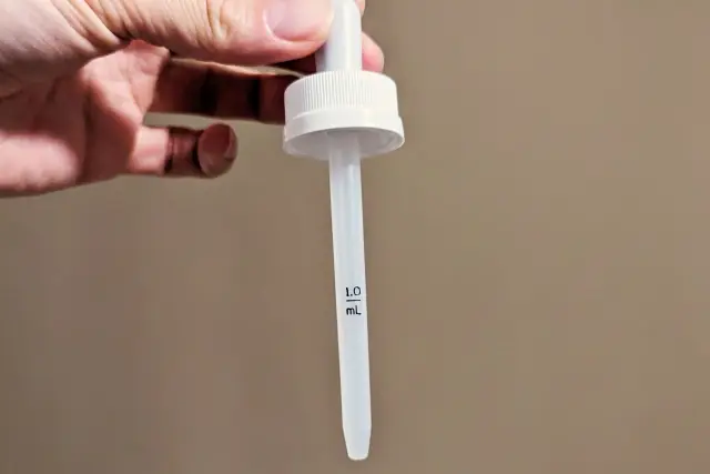 指先で持たれたスポイト容器。ミノキシジル外用薬などの育毛剤や美容液の塗布に使われる一般的なスポイトで、薄毛治療における使用例が増えていることを示すイメージ