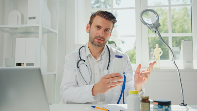 ヒゲのある欧米人男性医師がデスクで説明する様子。ヒゲ移植の専門性や信頼感を伝えるイメージカットとして使用。