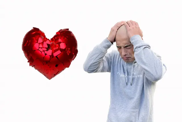 脱毛に悩む男性が頭を抱え、悲しげな表情を浮かべている。隣にはひび割れたハートのイラストが描かれ、若年性脱毛症による自己肯定感の低下や恋愛関係の喪失を象徴するイメージ。