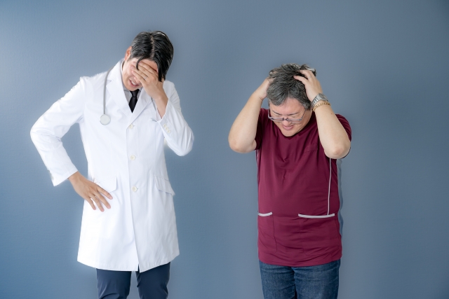 無資格者による植毛手術のリスクに直面し、頭を抱えて苦悩する医師と看護師のイメージ写真。医療ミスや違法な施術代行に対する医療現場の困惑と倫理的ジレンマを象徴するシーン。