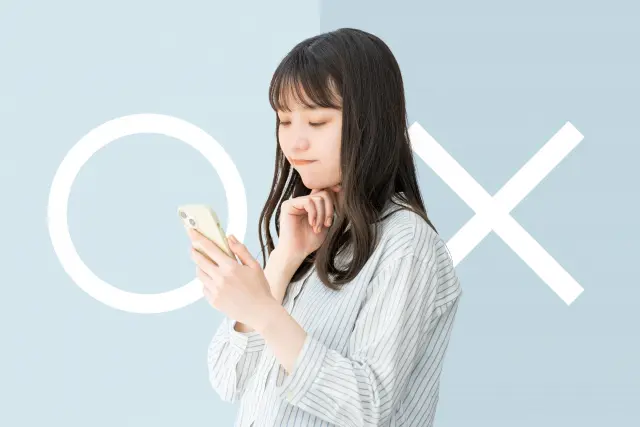 スマートフォンを見つめながら真剣に考え込む若い日本人女性 — 背景には「○（はい）」と「×（いいえ）」の選択肢が浮かび、髪を染めるべきか悩む姿を通じて、美容と健康リスクを天秤にかけた意思決定の難しさを表現