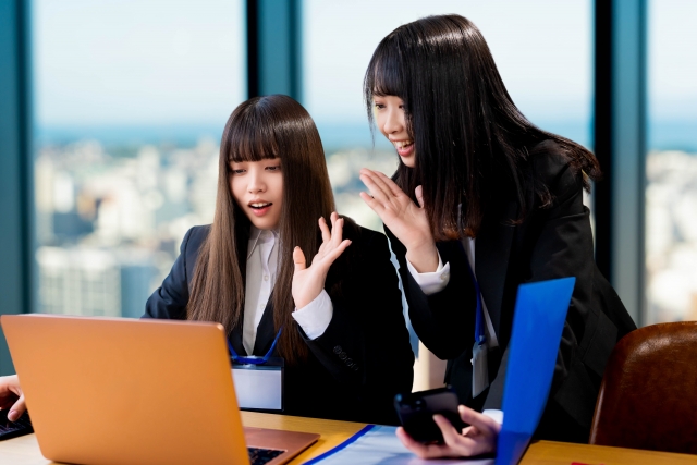 職場で手振りを交えて会話する女性たち。脱毛にまつわる俗説や噂話が日常会話で交わされる様子を表現したイメージ。