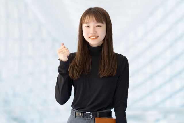 柔らかな笑顔を浮かべた日本人女性が、右手のこぶしをそっと握りしめながら、前向きな気持ちで励ますようなポーズをとっている様子。毛髪移植という選択に勇気をもって向き合う姿を象徴し、自然な美しさと自信を取り戻すプロセスを応援するイメージカット。