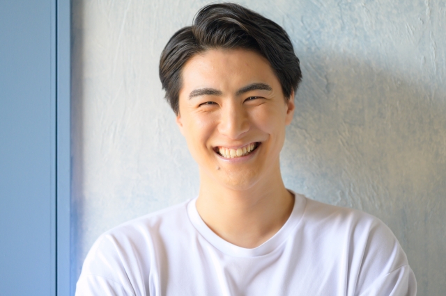 横分けに整えた髪型で笑顔を見せる若い男性。初期の薄毛を目立たせずにカバーするスタイリングの工夫を表現｜非手術的な薄毛対策としてのヘアスタイル演出の一例