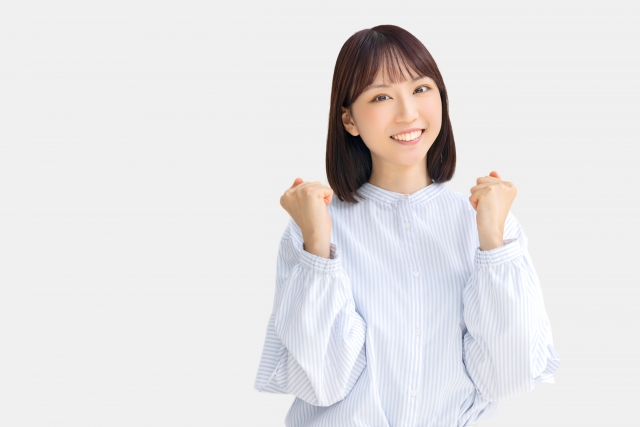 毛髪の成長や抜け毛からの回復に希望を見出し、両腕を曲げて喜びを表現する女性のポーズ写真。毛周期と幹細胞の役割を解説するコラム記事に関連する、達成感と前向きさを感じさせるイメージ