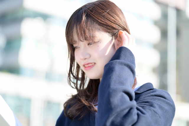 髪を耳にかけて穏やかに微笑む女性。髪の健康や抜け毛対策に関心を持つ現代女性のイメージ