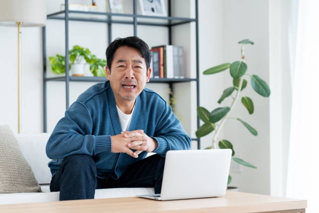 ノートパソコンの前に座り、後悔の表情を浮かべる男性。過去の薄毛治療で満足のいく結果が得られなかった経験を思い出しながら、新たなヘアリストレーション（hair restoration）プランを検討している様子。植毛や育毛対策における自己判断のリスクや、医師との相談の重要性を示唆するイメージ。