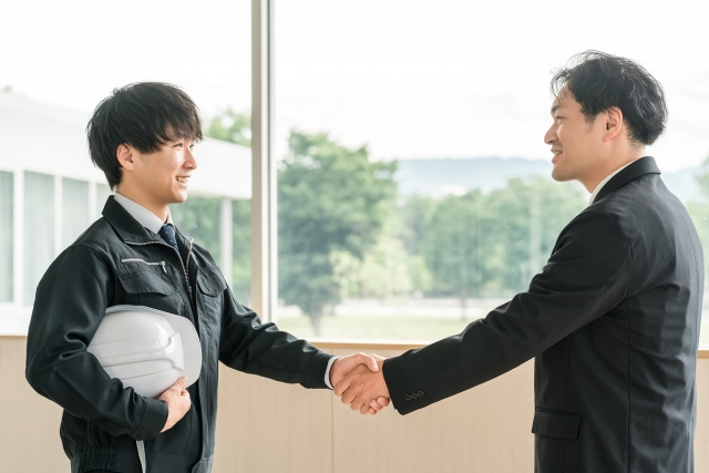 年上のビジネスメンターと握手を交わす若い男性の姿。世代を超えた信頼関係を象徴する場面であり、AGA（男性型脱毛症）の早期対策や専門医との相談の重要性を示唆する印象的なシーン｜ヒロクリニッ