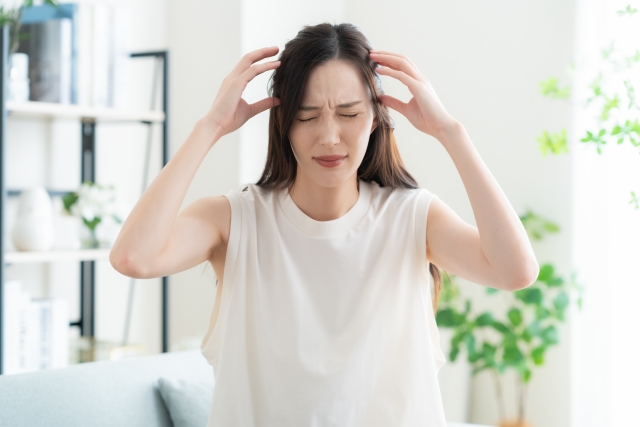 植毛手術後の違和感や頭皮の炎症に苦しむ女性患者のイメージ。無資格者による施術のリスクや不適切な手技による後遺症を象徴する痛みの表現。