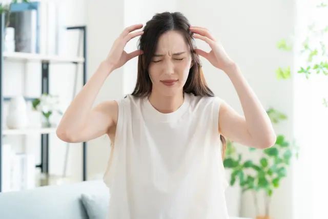 植毛手術後の違和感や頭皮の炎症に苦しむ女性患者のイメージ。無資格者による施術のリスクや不適切な手技による後遺症を象徴する痛みの表現。