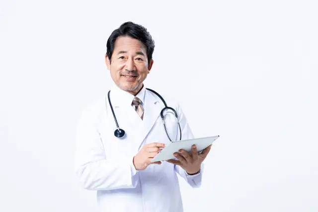 診療記録を手に微笑む医師の男性|植毛手術は医師の専門知識と外科的技術が必要であることを象徴するイメージ