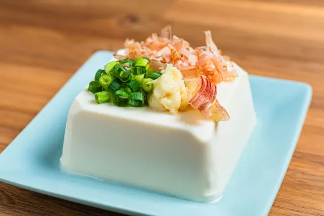 薬味としてネギとかつお節を添えた冷奴の一皿。大豆由来のイソフラボンを含む豆腐は、ポリフェノールと同様にホルモンバランスの調整や美肌・育毛をサポートする自然派食品の代表例。