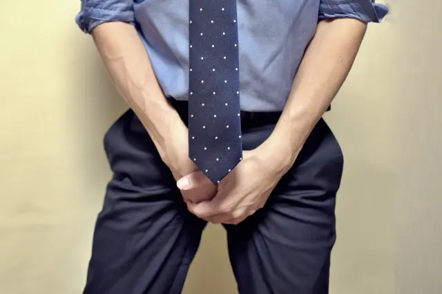 下腹部に強い違和感や痛みを感じている中年男性の下半身イメージ。前立腺トラブルや男性特有の体調不良の兆候を象徴的に示したビジュアル。男性型脱毛症と前立腺がんの関連を扱う医療コラムの装飾用画像