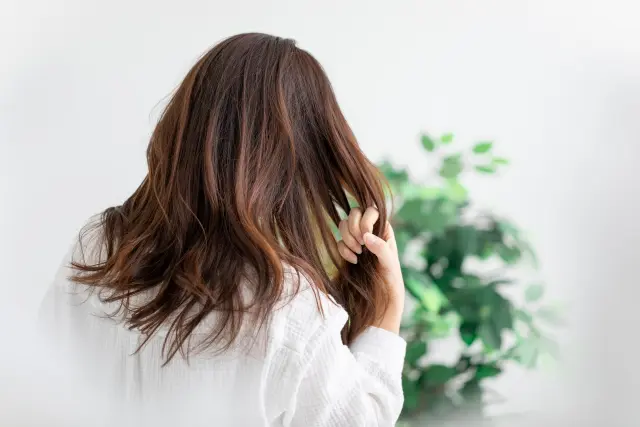 健やかな髪を指でなでるようにとかす人のイメージ。日々のヘアケアで頭皮環境をととのえる様子を表現。