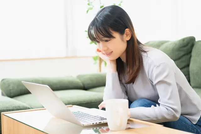 分け目の広がりや髪全体のボリューム低下を鏡で確かめる女性|女性の薄毛(びまん性脱毛)のイメージ