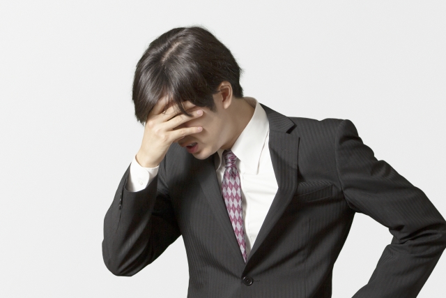 薄毛に悩み、人知れず苦しむ若い日本人男性のイメージ写真。自己肯定感の低下や見た目の不安を抱える20代男性が、職場やSNSでのストレスにより涙をこらえている様子を表現。若年性脱毛やAGAの心理的影響を示唆するビジュアル素材。