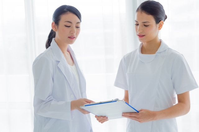 海外の医療現場で活躍する2人の看護師が、白衣を着てカルテを見ながら治療内容を確認している様子。グローバルな医療ツーリズムにおける現地医療スタッフとのやり取りや、海外クリニックの信頼性を象徴するイメージとして使用。