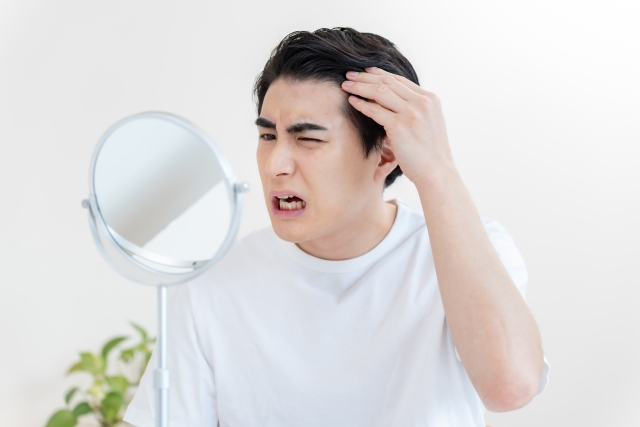 鏡で生え際を見る男性