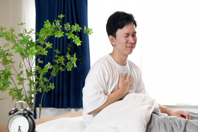 胸を苦しそうに抑える寝起きの男性