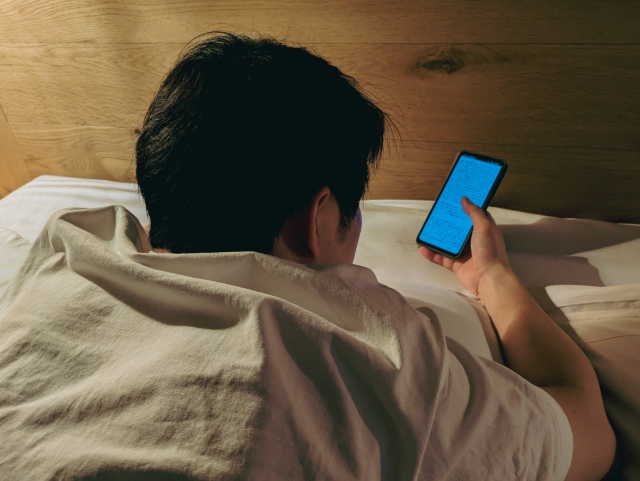ベッドでスマホを触る男性