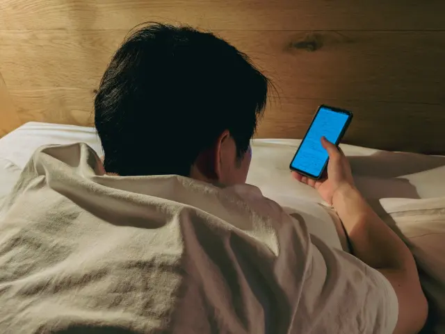 ベッドでスマホを触る男性