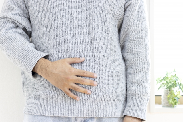 お腹に手を当てる男性