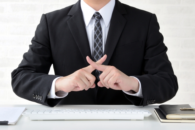 指でバツをつくるビジネスマン