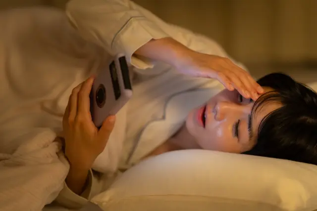 ベッドでスマホを触る女性