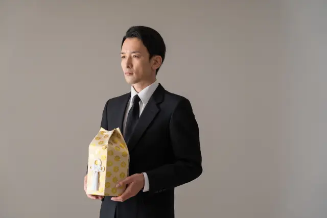 遺骨を手にする男性のイメージ