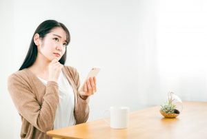 スマホを見て悩む女性