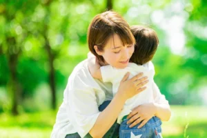 A mother gently hugging her child, expressing love and support for autism spectrum disorder（自閉スペクトラム症の子どもをやさしく抱きしめる母親）