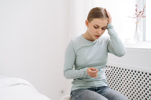 妊娠検査薬を見て悩む女性