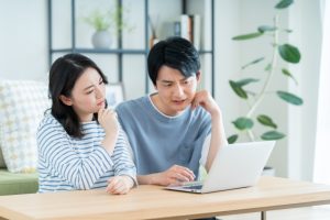 夫婦でPCを見ながらほほえむ