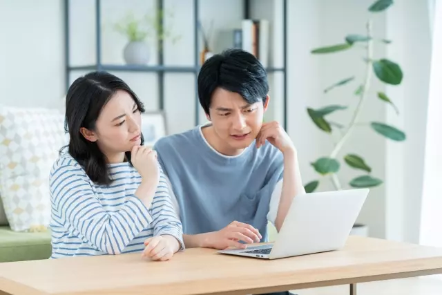 夫婦でPCを見ながらほほえむ