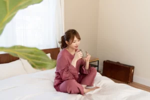 ベッドの上でコップを持つ女性